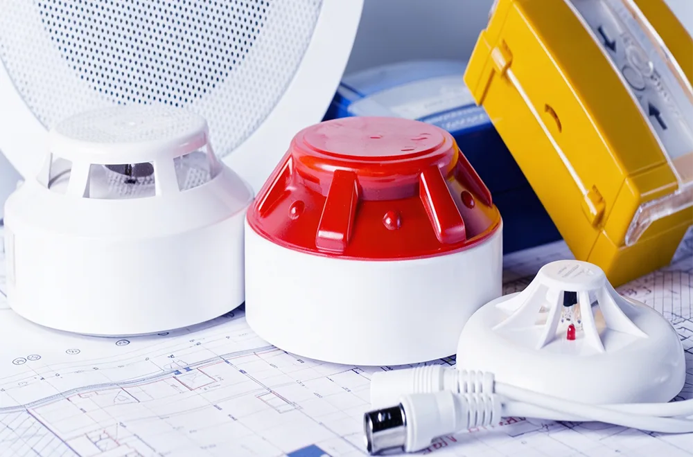 smoke alarms placed on a table over fire safety plans